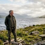 Man stands quietly by Loch Lomond shore