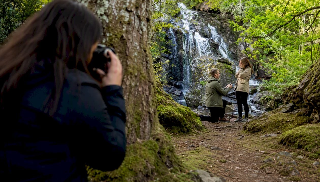Hidden photographer filming proposal near waterfall