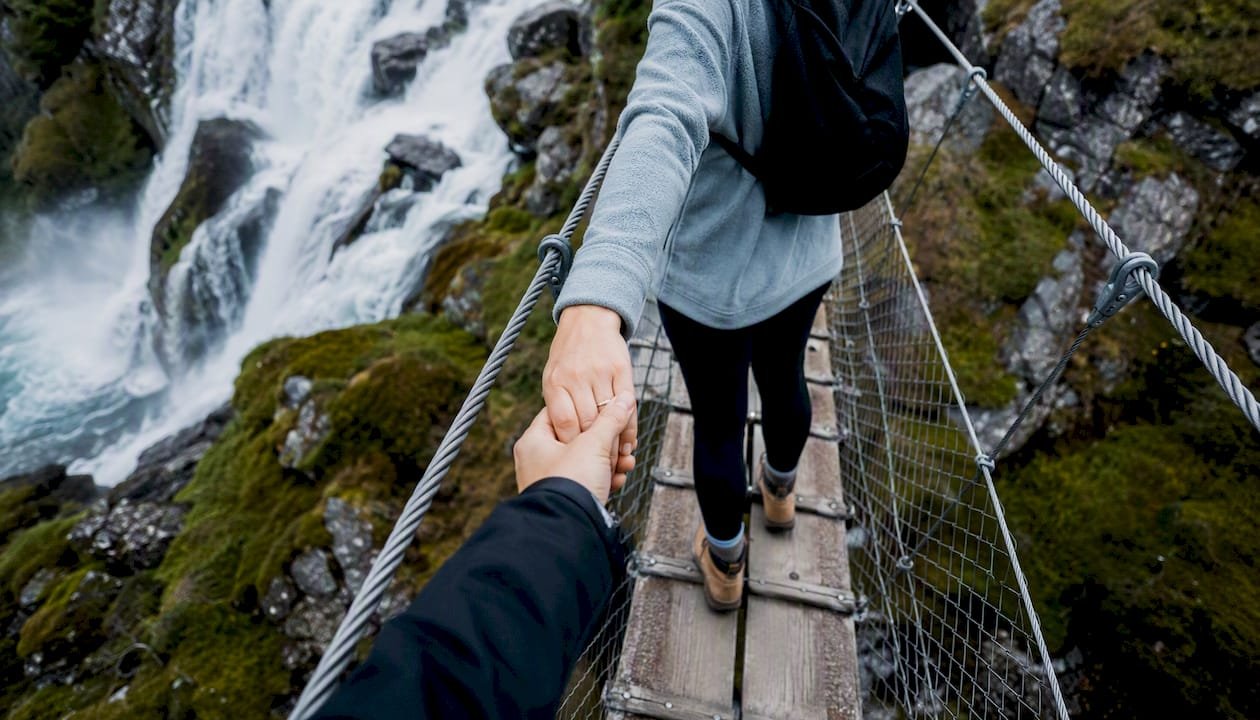 Couple crossing rope bridge at Steall Falls