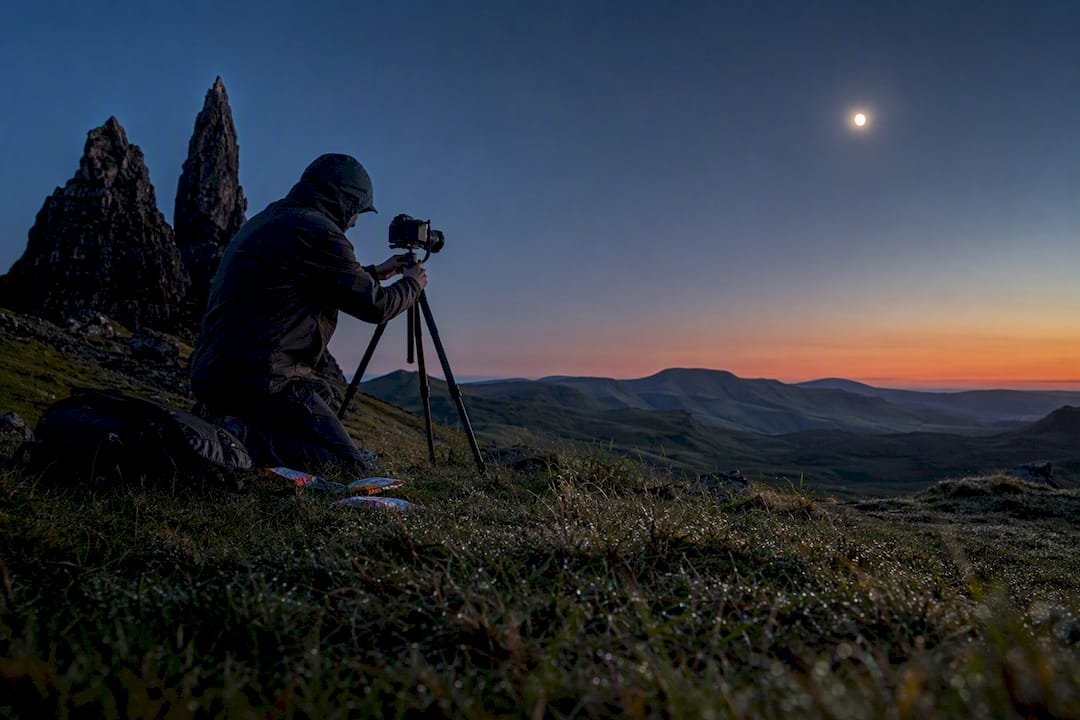 Photographer adjusting tripod on Highland hill