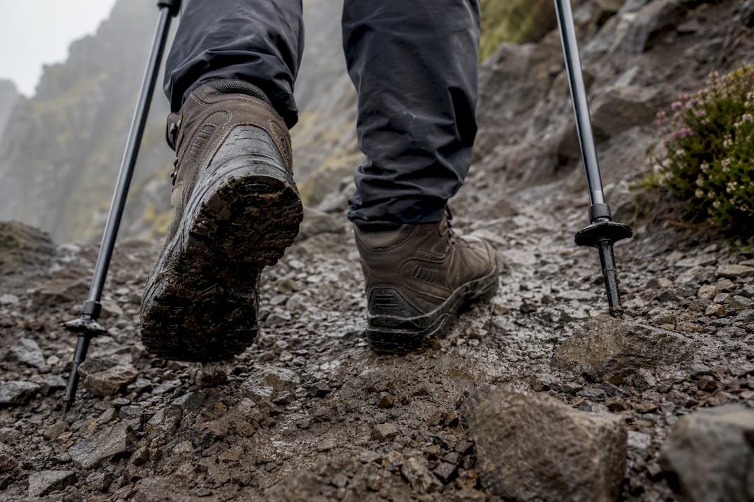 Walking boots and poles on muddy Storr path