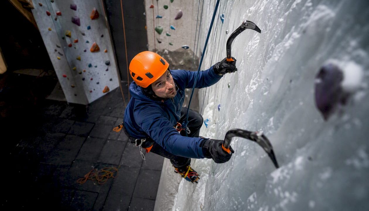Ice climber ascending indoor ice climbing wall