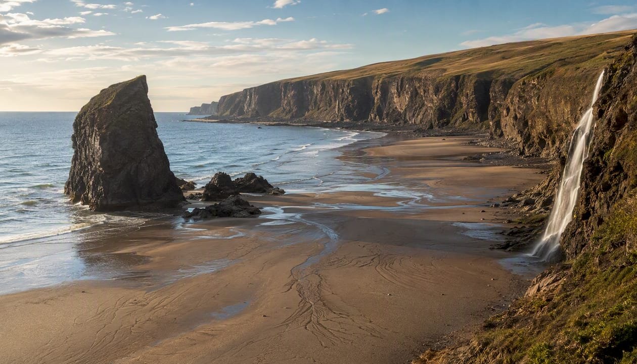 Talisker Bay beach with sea stack and waterfall at low tide
